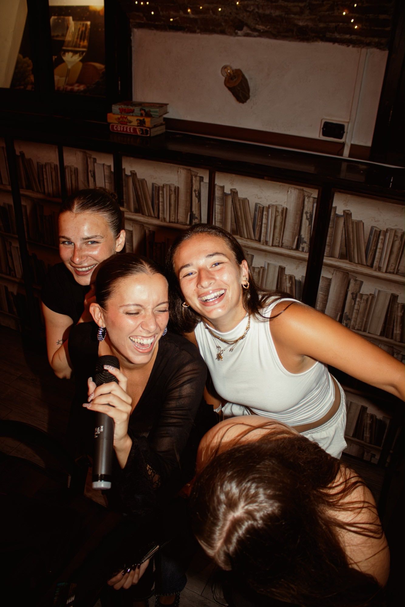 Un gruppo di amiche ride davanti alla libreria mentre una canta al microfono